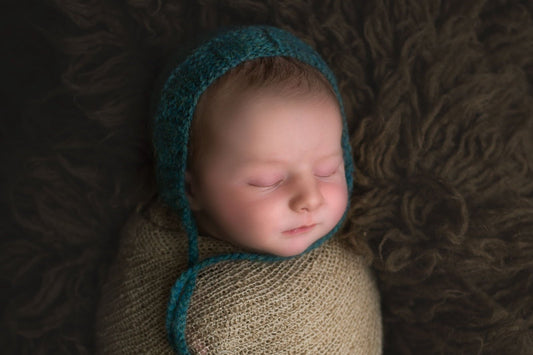 Snuggly newborn baby wrapped and wearing a blue bonnet